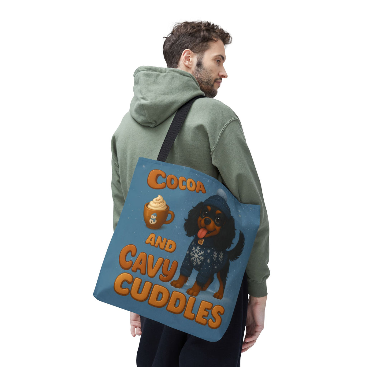Man in a green hoodie carrying the Black and Tan Cavalier Cocoa and Cavy Cuddles tote over his shoulder, back view