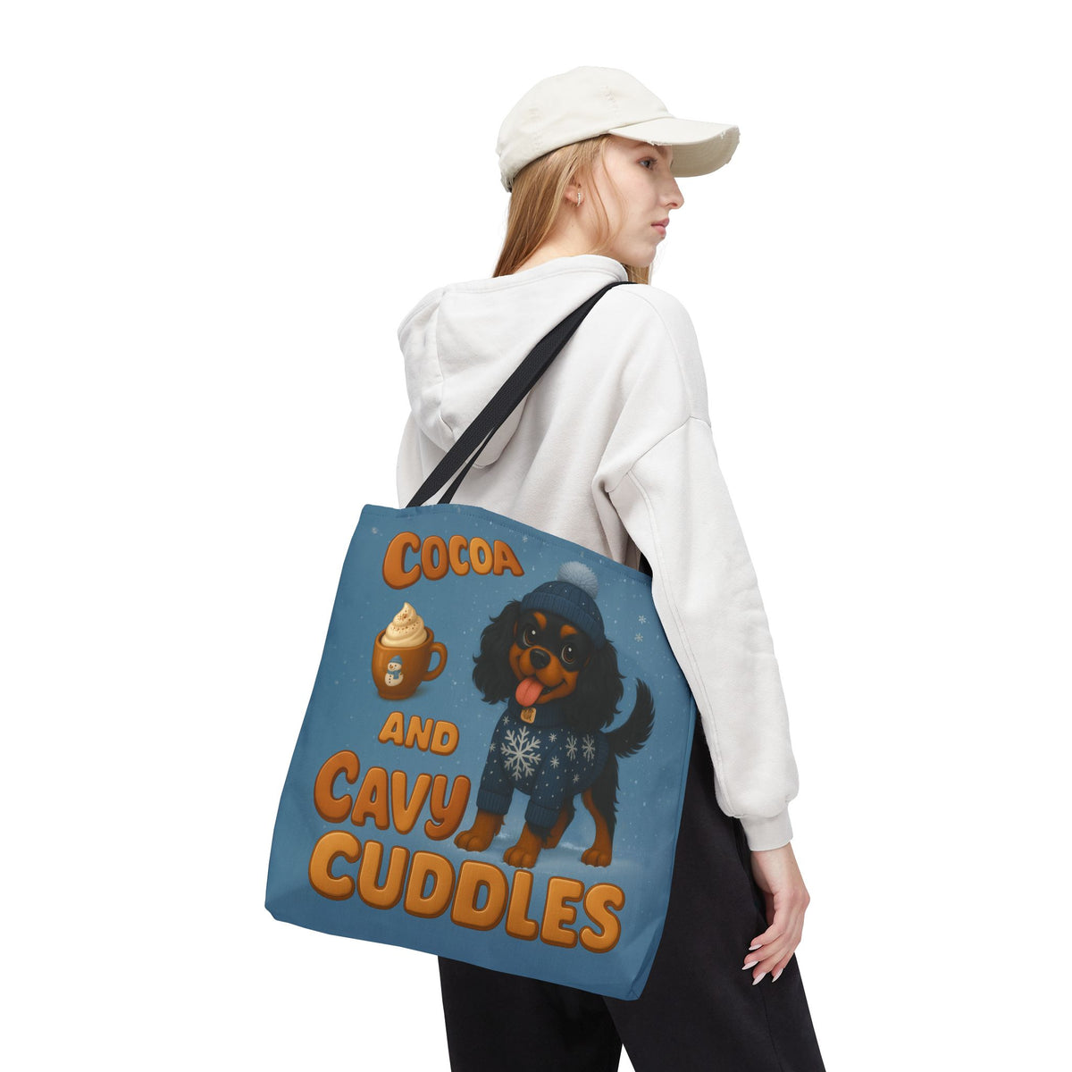 Woman in a cap carrying the Black and Tan Cavalier Cocoa and Cavy Cuddles tote over her shoulder, back view