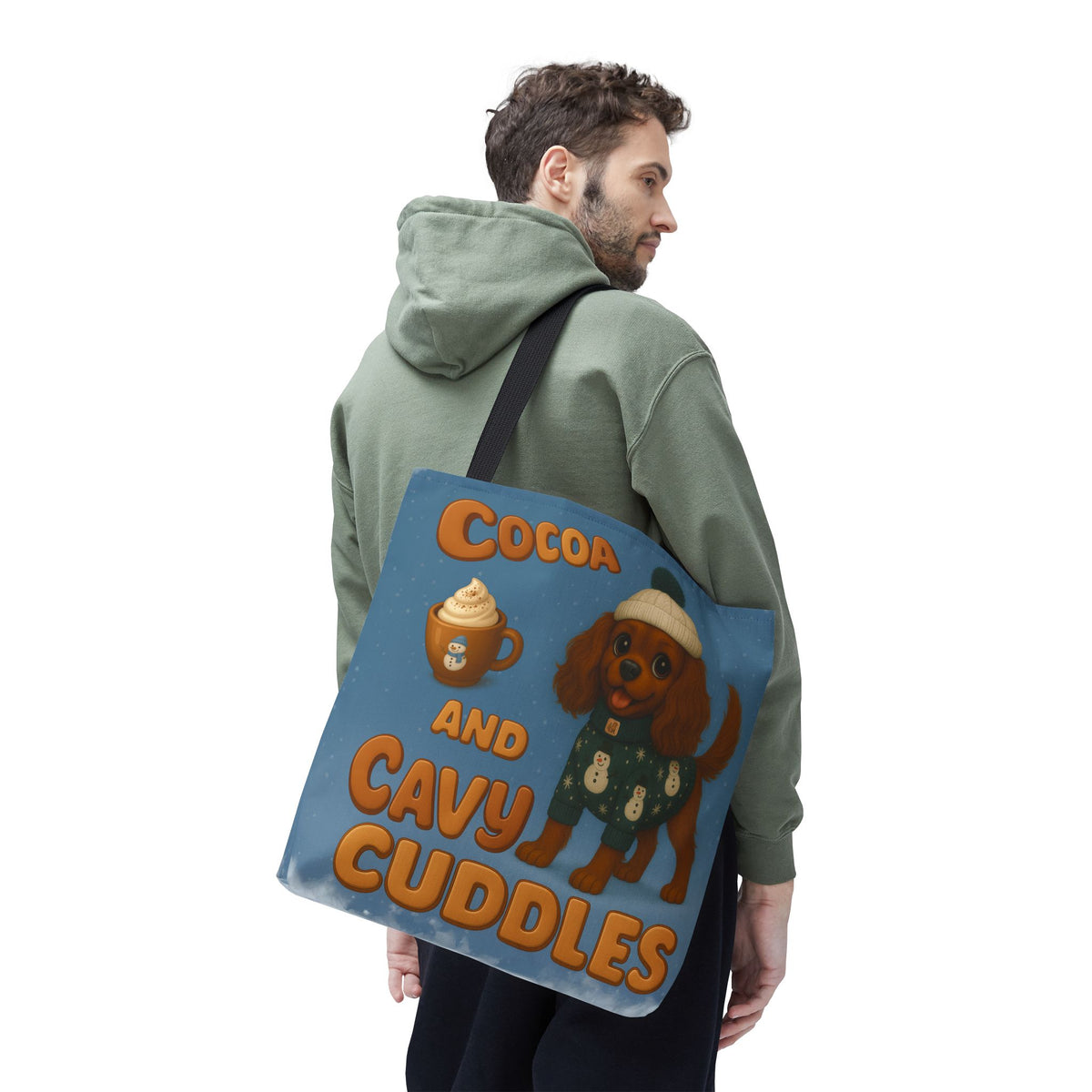 Man in a green hoodie carrying the Ruby Cavalier Cocoa and Cavy Cuddles tote over his shoulder, back view