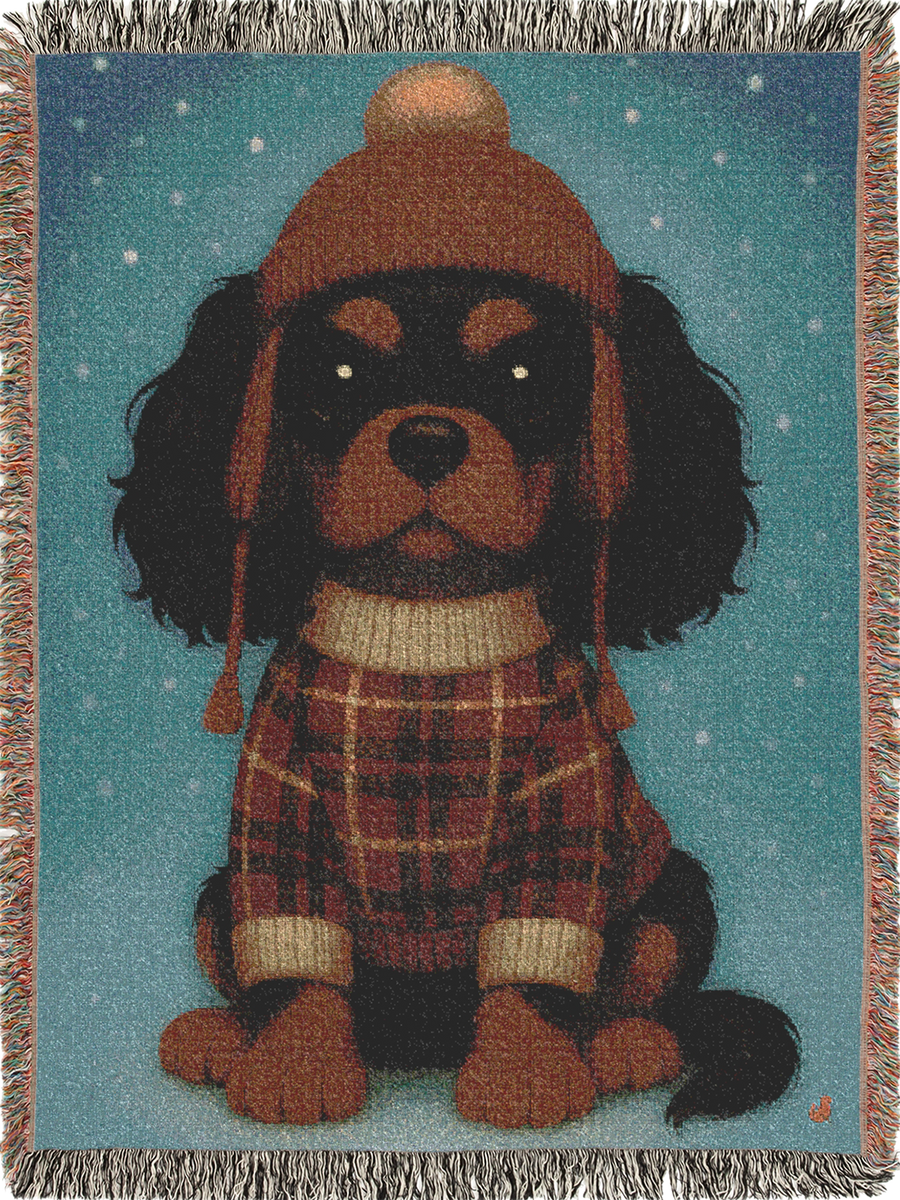 Cavy Comfort woven throw blanket, front view with fringed edges, Black and Tan Cavalier King Charles Spaniel puppy in a knit beanie and sweater in the snow